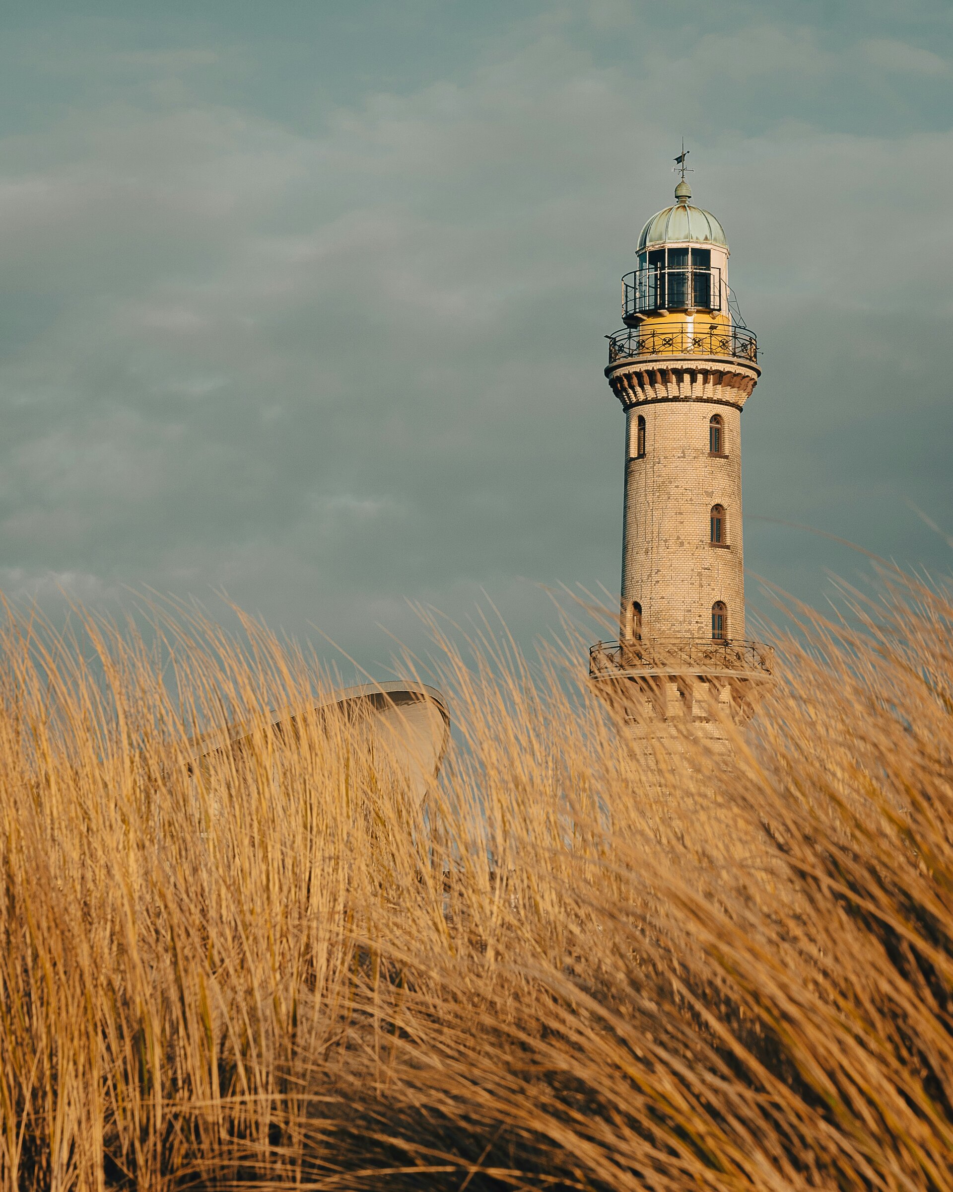 Fotospot Leuchttrum Warnemünde: Im Frühling am Strand von Warnemünde mit Blick auf den Leuchtturm bei Sonnenuntergang.