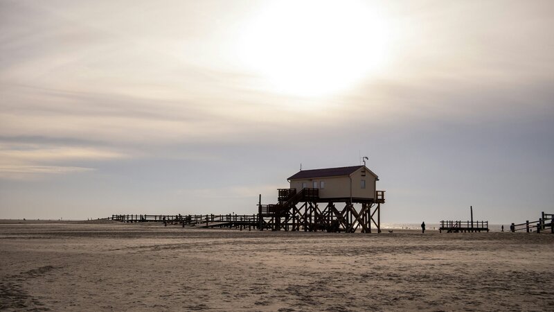 a house on a beach with a pier in the background