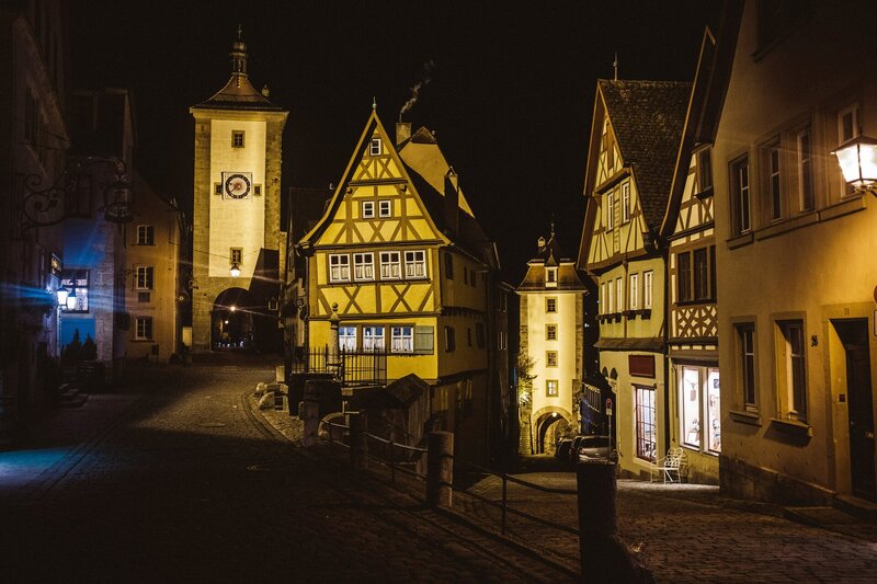 a street at night with a clock tower in the background