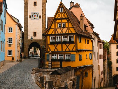 Plönlein: a cobblestone road with a yellow building and a clock tower in the background