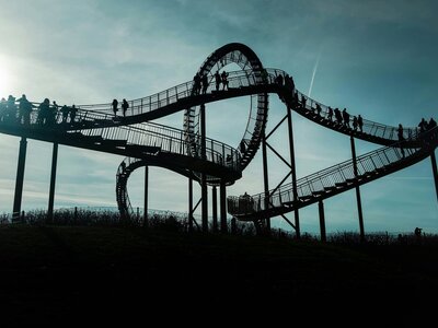 Tiger & Turtle: gray metal bridge under white clouds